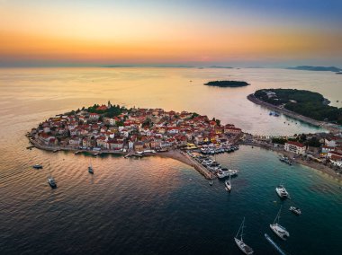 Primosten, Hırvatistan - Hırvatistan 'ın Dalmaçya kentinde güneşli bir yaz sabahı, Adriyatik deniz kıyısında gün doğumunda mavi ve altın gökyüzü ile Primosten yarımadası ve eski kentin havadan görünüşü