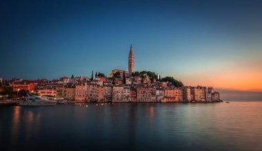 Rovinj, Hırvatistan - Adriyatik deniz kıyısındaki Aziz Euphemia kilisesi ile güzel Rovinj Eski Kent 'in günbatımı manzarası. Açık mavi gökyüzü, altın günbatımı renkleri