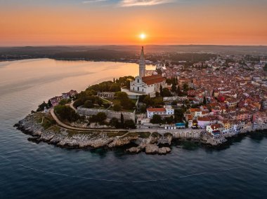 Rovinj, Hırvatistan - St. Euphemia Kilisesi ile eski Rovinj kasabasının havadan görünüşü ve Hırvatistan 'ın Istria kentinde bir yaz sabahı doğan güneş. Altın ve mavi gökyüzü ve Adriyatik Denizi 'nin yükselen güneşi