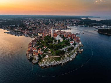 Rovinj, Hırvatistan - St. Euphemia Kilisesi ile eski Rovinj kasabasının havadan görünüşü ve Hırvatistan 'ın Istria kentinde bir yaz sabahı doğan güneş. Adriyatik Denizi kıyısında altın gökyüzü ve kırmızı çatılar