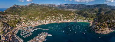 Mallorca, İspanya - Mavi gökyüzü, bulutlar, yat marinası ve arka planda dağlarla birlikte Mallorca adasındaki Akdeniz şehri Port de Soller 'in panoramik hava manzarası