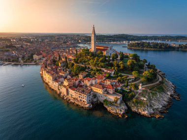 Rovinj, Hırvatistan - St. Euphemia Kilisesi ile eski Rovinj kasabasının havadan görünüşü ve Hırvatistan 'ın Istria kentinde bir yaz sabahı doğan güneş. Adriyatik Denizi kıyısında altın gökyüzü ve kırmızı çatılar