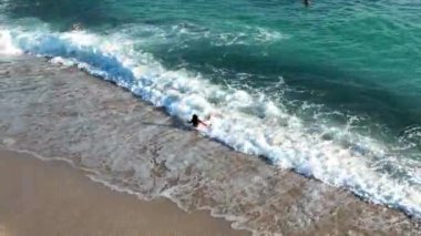 Genç bir kız dalgalarla mutlu bir şekilde savaşıyor.