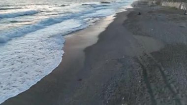 Bir adam kumsal mavisi deniz dokusunda koşar.