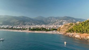 Mavi deniz ve liman kenti arka planıyla Alanya plajı dağ manzaralı.