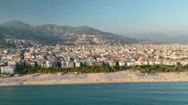 Mavi deniz ve liman kenti arka planıyla Alanya plajı dağ manzaralı.