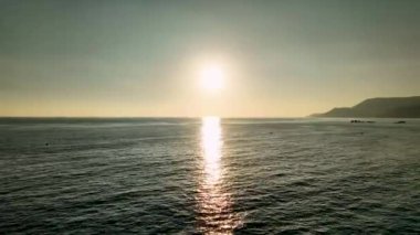 Bir tatil beldesinde deniz kıyısında bulutsuz bir günbatımının hava görüntüsü..