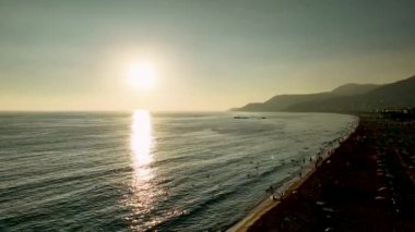Bir tatil beldesinde deniz kıyısında bulutsuz bir günbatımının hava görüntüsü..