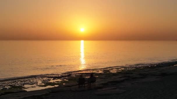 Κόσμος Κάθεται Στην Παραλία Και Βλέπει Ηλιοβασίλεμα — Αρχείο Βίντεο