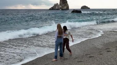 Dalgaların ve ufuktaki mavi gökyüzünün arkaplanına doğru yürü. bulutlu bir günde tatil