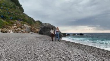 Dalgaların ve ufuktaki mavi gökyüzünün arkaplanına doğru yürü. bulutlu bir günde tatil