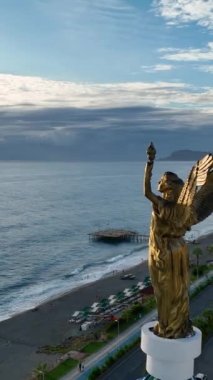 Evin çatısındaki bir melek heykeli bulutlu bir günbatımının arka planına karşı.