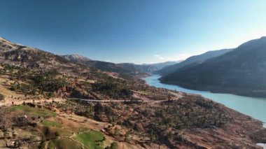 The water is rushing along colorful stones aerial view 4K flowing in the deep lake