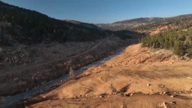 The water is rushing along colorful stones aerial view 4K flowing in the deep lake