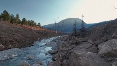 The water is rushing along colorful stones aerial view 4K flowing in the deep lake