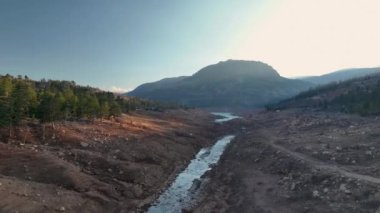 The water is rushing along colorful stones aerial view 4K flowing in the deep lake