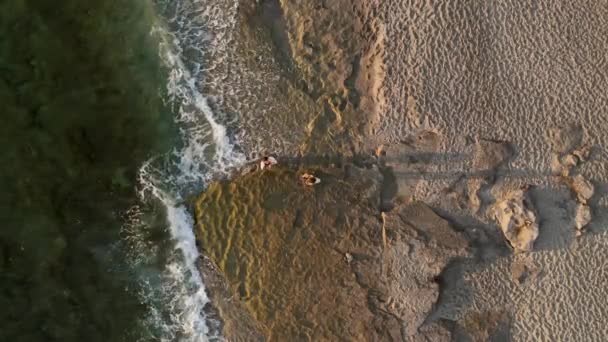 石のビーチにポーズを取る白いパレオのモデル — ストック動画