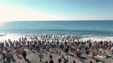 Bir rahip ve bir grup insan sahilde bir vaftiz töreni düzenliyor.