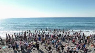 Bir rahip ve bir grup insan sahilde bir vaftiz töreni düzenliyor.