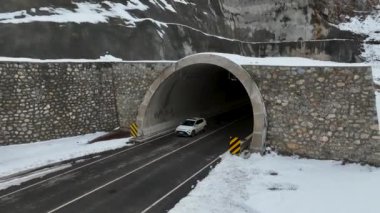Kışın asfalt yolda. Kış manzarasında araba gezisi. Ormanlık alanda garaj yolu. Buzlu ve soğuk bir günde yollarda seyahat etmek.