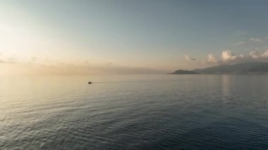 Beyaz küçük motorlu tekne derin mavi sularda yol alır - havadan çekilen görüntüyü izler