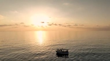 İnsansız hava aracı, güneşli bir günde, bulutlu gökyüzünün altında dalgalanan deniz suyunda yüzen gerçek zamanlı tur teknesinin görüntüsü.