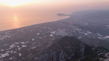Şehir manzarasına tepeden bakan bir dağın arkasından kalkış.