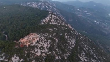 4K hava aracı, bir patika ve gökyüzü ile kayaların ve sık orman dağlarının üzerinden geçiyor..