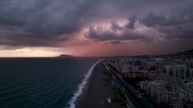 Denizin arka planı, güneş batar, gökyüzünde kırmızı ve turuncu bulutlar akar. Görkemli bahar manzarası. Gün batımının peyzaj süresi