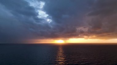 Denizde romantik, renkli bir gün batımı. Denizin arka planında, güneş batar, mavi ve turuncu bulutlar gökyüzünde akar. Görkemli bahar manzarası. Gün batımının peyzaj süresi