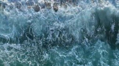 Yukarıdan aşağıya soyut hava manzaralı okyanus dalgaları kayalık kıyı şeridine çarpıyor.
