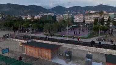 Kırmızı bir basketbol sahasından insansız hava aracına yumuşak bir tırmanış, insanlar aktif olarak top oynuyorlar.