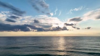 Golden sunset on a beach - slow motion of foamy waves rolling towards white sand beach under low the sun light