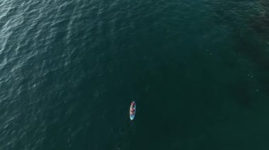 Sörf tahtasında yatan çiftler, mavi sörf tahtasında dinlenen kadın ve erkek yüzücüler. Göldeki yiyecek panolarında insanların profesyonel insansız hava araçlarıyla vurulması. Doğa ve sakinlik.