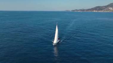 İçinde insanlar olan beyaz bir yelkenli. Akdeniz 'de yüzüyor. Lipari Adaları. Sicilya, İtalya. Ufuk, mavi gökyüzü