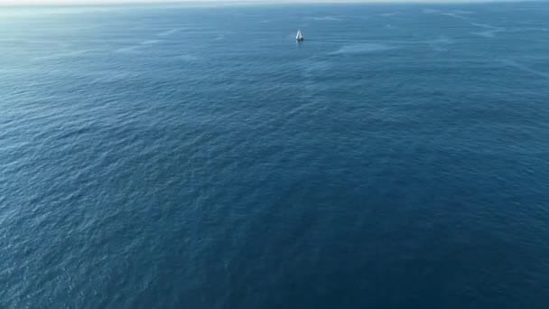 開放的な海の空の景色の中で夕日に浮かぶ波に反射してヨットをセーリング 海の湾を巡航する帆船との自然景観 夏休みの風景 — ストック動画