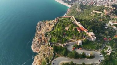 Harabeler ve kayalık tepelerdeki tarihi Alanya kale duvarları ve yelkenli gemiyle donatılmış gök mavisi Akdeniz 'in arka planındaki riff' ler etrafındaki hava manzarası. Antalya İli, Türkiye, 4k görüntü