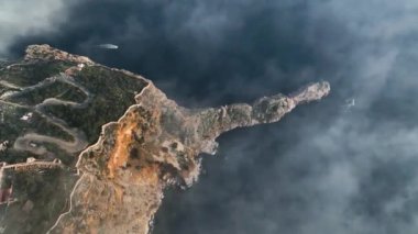 Ufuktaki bulutlarda uçan bir dronun destansı kuş bakışı görüntüsü Alanya şehrindeki görkemli bir kayadır.