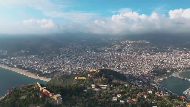 从鸟瞰的角度来看 阿拉亚是土耳其的一个城市 住宅建筑 道路和基础设施的空中景观 地中海沿岸的一个旅游城镇 具有山脉 天空和海洋的城市景观 — 图库视频影像