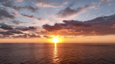 Aerial view of sunset horizon over the sea. Cinematic drone aerial view beautiful evening sunset in sky over sea. Sun path is reflected in sea surface. Nature beauty.