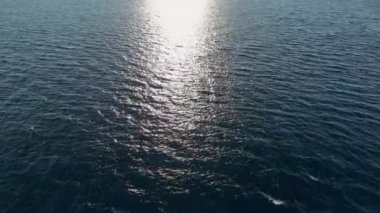 Açık havada beyaz dalgalı mavi deniz tarağı. Açık gök mavisi denizde deniz havası. Dalgalanan deniz dokusunun hareketli yüzeyine gemiden bak. Karanlık okyanus suyu. 4k