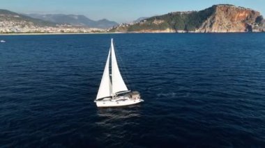 Rüzgâr teknesi denizde, nehirde, göl suyunda, güneşli bir günde yelken açıyor. Küçük bir balıkçı gemisinin üst hava manzarası. Okyanus tatili, dinlenme, yatta dinlenme. Yaz tatili