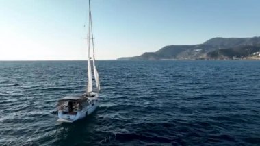 Rüzgâr teknesi denizde, nehirde, göl suyunda, güneşli bir günde yelken açıyor. Küçük bir balıkçı gemisinin üst hava manzarası. Okyanus tatili, dinlenme, yatta dinlenme. Yaz tatili