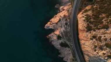 Yol manzaralı Alanya kıyı şeridi üzerinde uçan insansız hava aracı, bitki örtüsü ve kayalarla kayalık kıyı şeridi ve açık köpüklü dalgalarla açık deniz