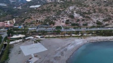 Yol manzaralı Alanya kıyı şeridi üzerinde uçan insansız hava aracı, bitki örtüsü ve kayalarla kayalık kıyı şeridi ve açık köpüklü dalgalarla açık deniz
