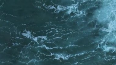 Hava aracı, gün batımında ıssız bir plajın üzerinden alçaktan uçuyor. Yuvarlanan dalgalarla kumsal kıyısı ve ufukta batan güneş. Deniz Burnu