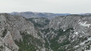 Bir yola bakan hava manzarası, karla kaplı ağaçlar ve karlı ormanın ortasında, karanlık, bulutlu bir kış gününde - tepeden aşağı, drone çekimi