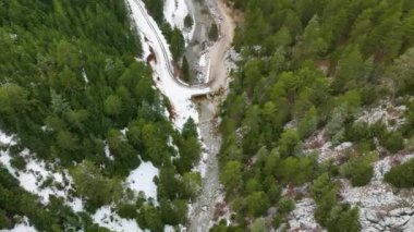 Karla kaplı ağaçların ve karlı ormanın ortasında donmuş bulutlu bir kış gününde yola bakan hava manzarası. Yüksek kalite.