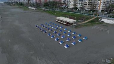 Alanya 'daki bulutlu havaya rağmen kumsalda şezlonglu sandalyeleri olan deniz kenarındaki bir kafeyi ele geçiren dronumuz sinemanın tadını çıkarın. Çarpıcı görüntüler ve kıyı konsepti hazırlansın.