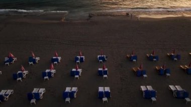 İnsansız hava aracımız alacakaranlıkta boş şezlongların sabit dikey çekimini yaparken Alanyas turizm krizinin büyüleyici güzelliğini tecrübe edin. Görüntü içeriğinizi çarpıcı görsellerle yükseltin.